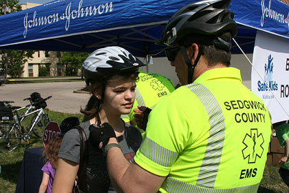 Sedgwick County EMS Bike Medic fitting a young girl with a bicycle helmet.