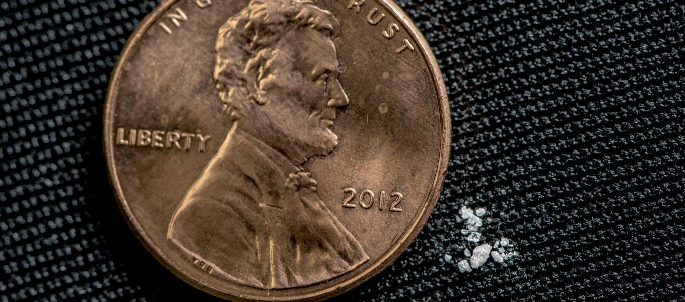 This picture shows a small amount of fentanyl in a crystalized form next to a penny for scale.
